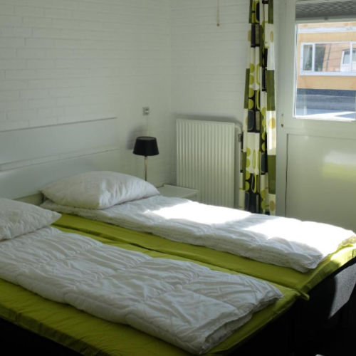 Værelse med senge og vinduer på hostel i Løkken